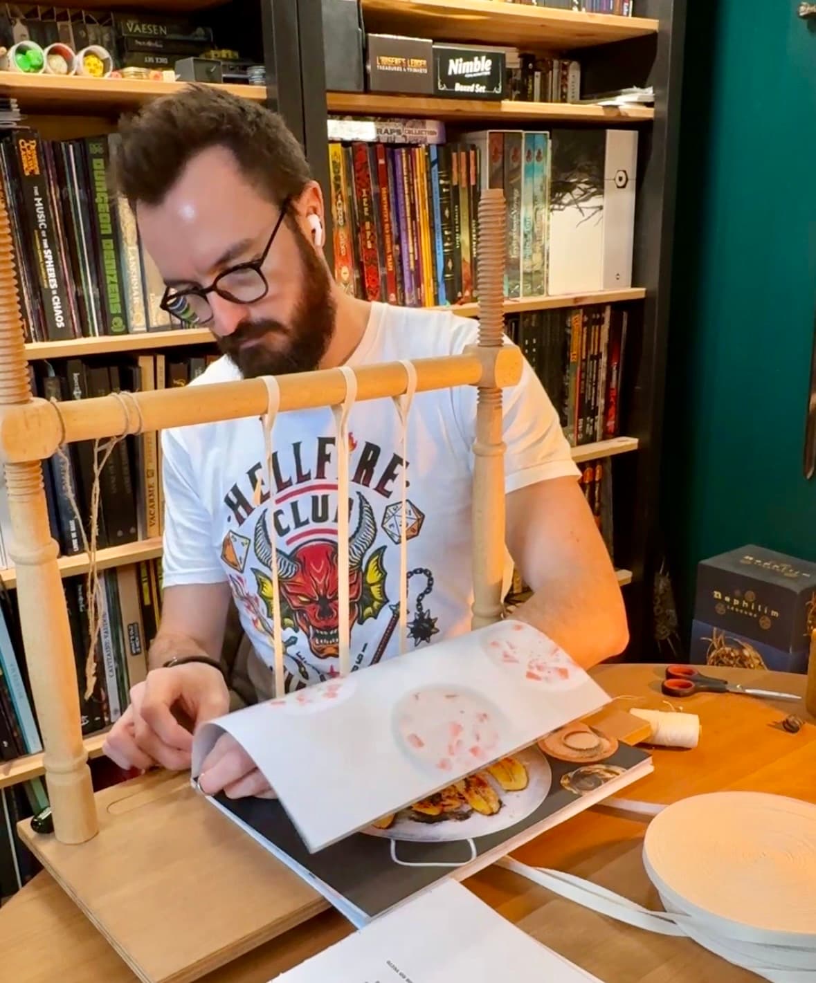 L'artisan de CorshCrafts coud le dos d'un livre sur son cousoir